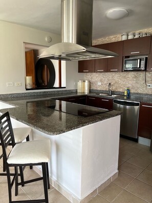 A modern kitchen with a central island, stainless steel appliances, and a microwave above the counter. - Caribbean Ocean View 3-BR Villa with Panoramic Ocean Views & 2 Private Terraces (Humacao)
