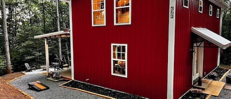 Un bâtiment rouge doté de nombreuses fenêtres, d’un porche couvert et d’une allée gravillonnée.