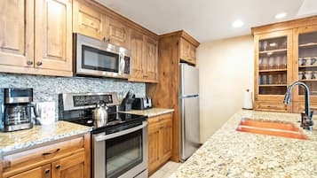 A kitchen with wooden cabinets, stainless steel appliances, granite countertops, and a built-in sink.