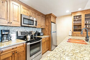A kitchen with wooden cabinets, stainless steel appliances, granite countertops, and a built-in sink. - Borders Lodge L308 2BD Beaver Creek Ski-in, Ski-out Condo (Avon)