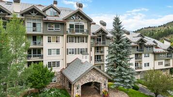 A multi-story hotel with balconies, a stone entrance, and a landscaped garden.