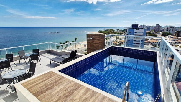A rooftop pool with a view of the ocean and cityscape. - COPIA0106 - Edifício Essencial Piata (Salvador)