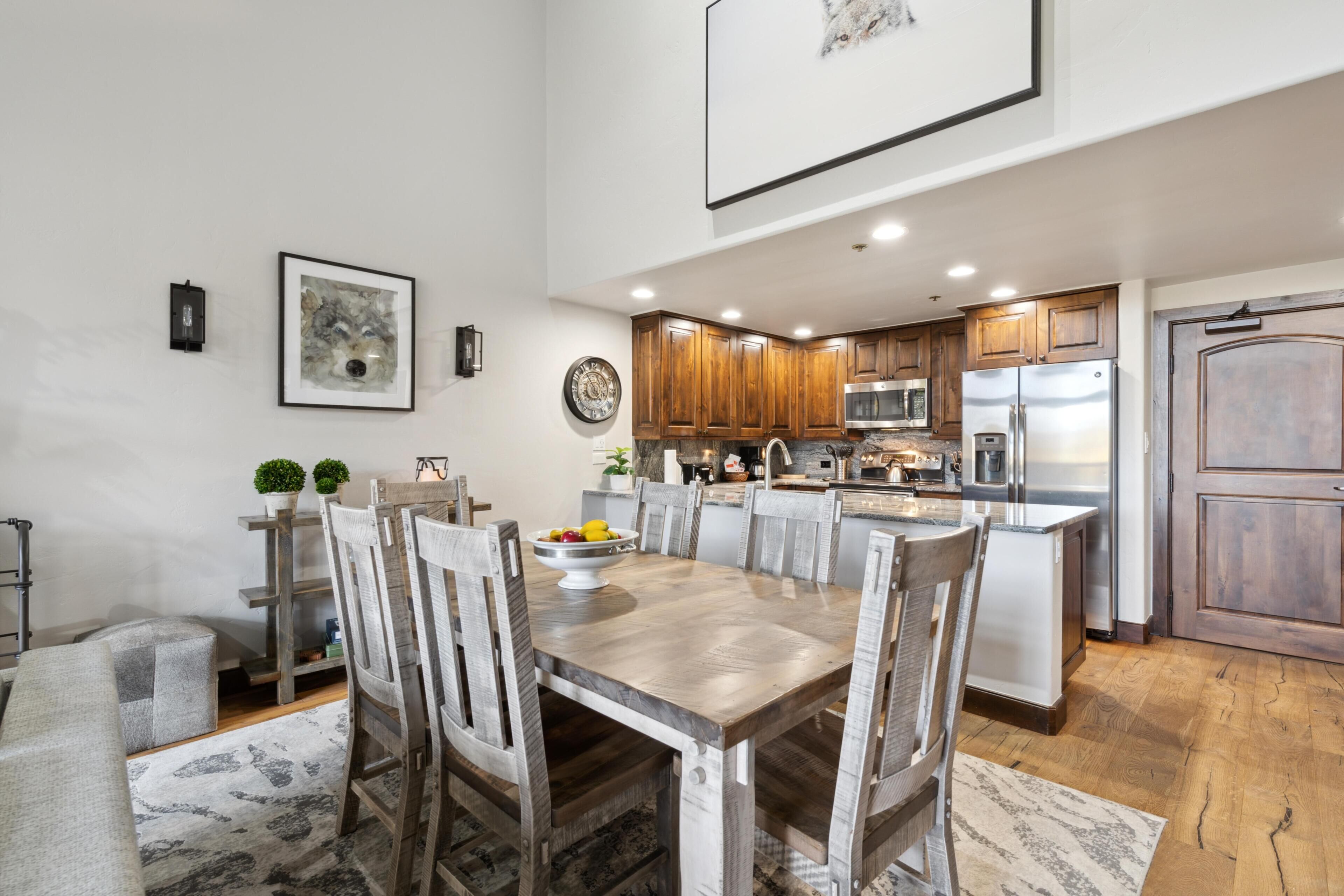 A modern kitchen with wooden cabinets, stainless steel appliances, and a dining area with a wooden table and chairs.