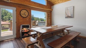 Een houten interieur met een grote tafel, banken, een klok en een schilderij van een zeilboot.