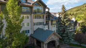 A multi-story hotel with a stone entrance, balconies, and a view of the surrounding landscape.