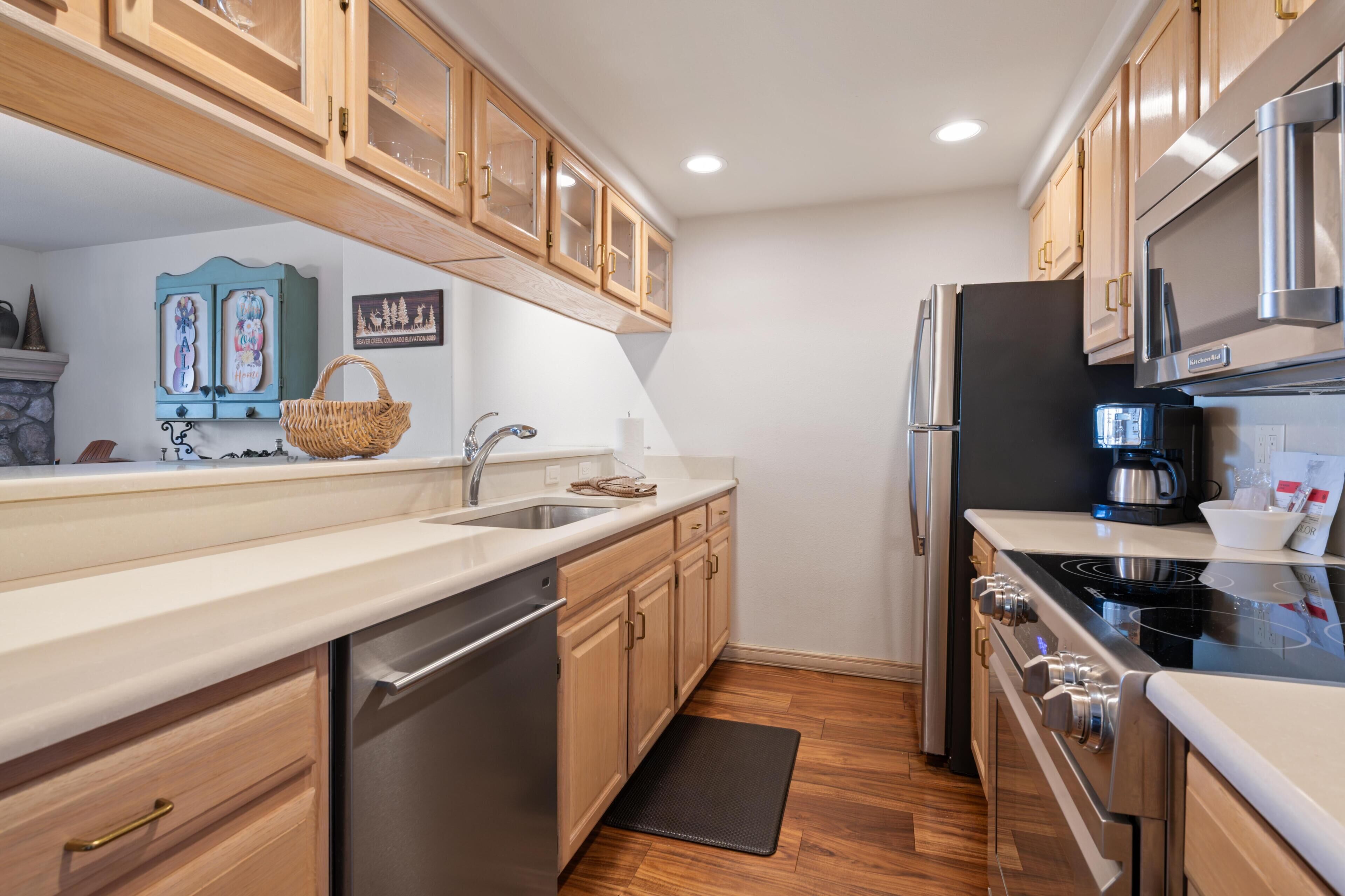A modern kitchen with wooden cabinets, stainless steel appliances, and a black countertop.