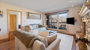 A living room with a sofa, a coffee table, a TV, and a fireplace. - Borders Lodge L403 2BD Beaver Creek Ski-in, Ski-out Condo (Avon)