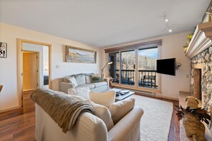 A living room with a sofa, a coffee table, a TV, and a fireplace. - Borders Lodge L403 2BD Beaver Creek Ski-in, Ski-out Condo (Avon)