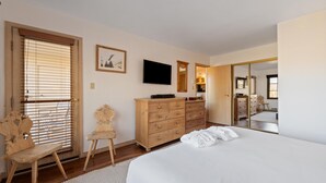 A bedroom with a bed, wooden dresser, TV, and a mirror. - Borders Lodge L403 2BD Beaver Creek Ski-in, Ski-out Condo (Avon)