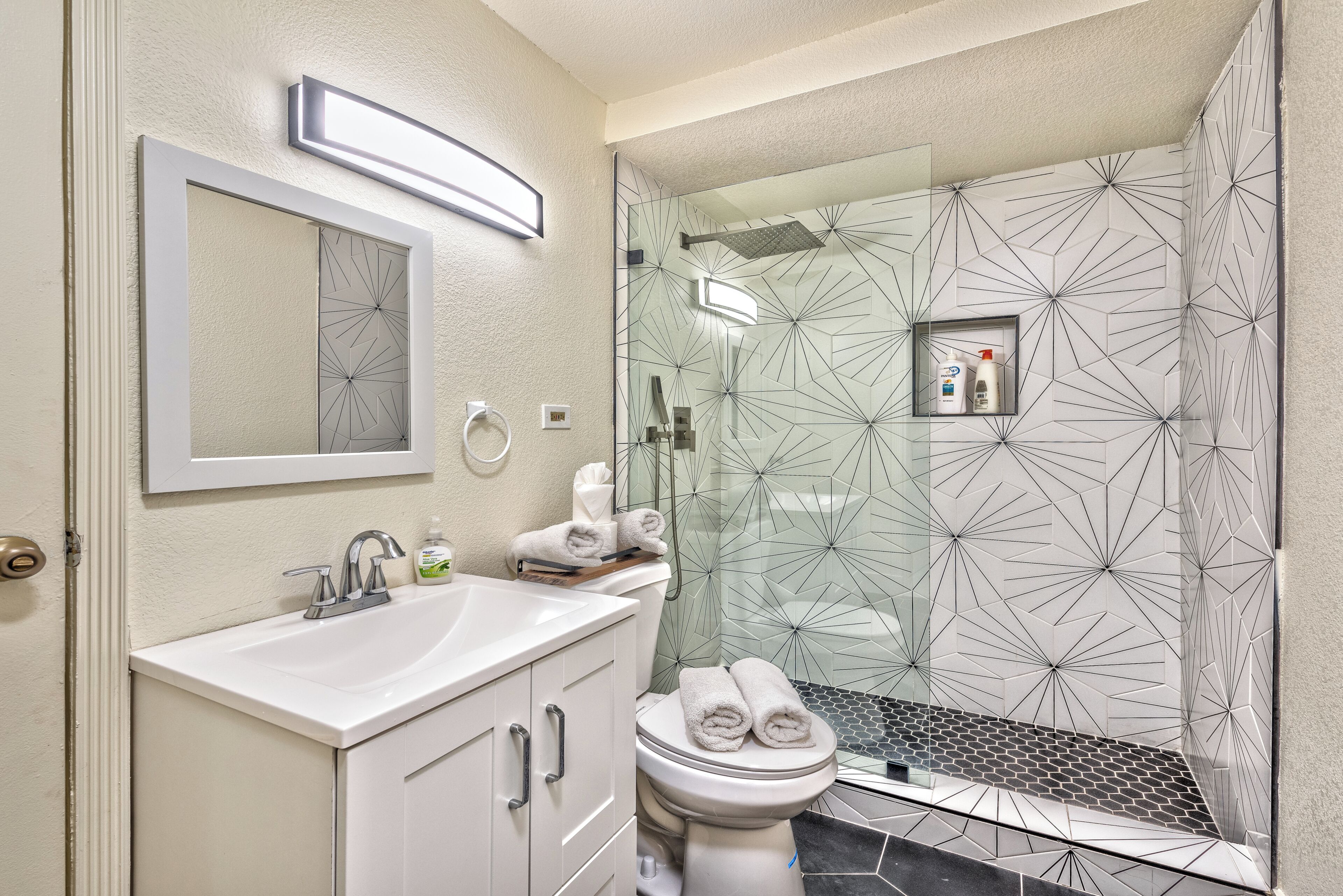 A modern bathroom with a glass shower enclosure, a white sink, and a toilet.