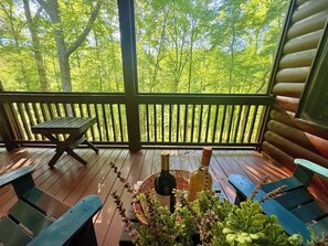 Eine Holzterrasse mit Tisch und Bänken, einer Flasche und einem Glas.