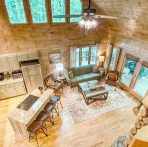 A spacious cabin with a kitchen, dining area, and living room, featuring wooden walls and large windows.