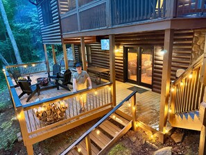 Eine Holzterrasse mit Sitzgelegenheiten im Freien, einer Feuerstelle und einer Treppe, die zu einer Hütte führt.