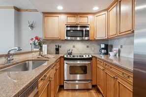 A kitchen with wooden cabinets, stainless steel appliances, granite countertops, and a backsplash. - Borders Lodge L406 3BD Beaver Creek Ski-in, Ski-out Condo (Avon)