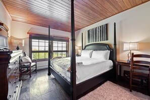 Ein Bett mit Baldachin, ein Kopfteil, ein Holztisch, ein Stuhl, eine Kommode und ein Fenster mit Blick.