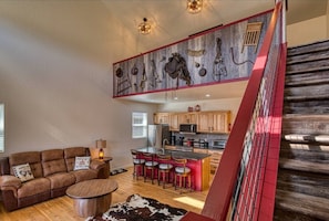 A spacious living area with a sofa, a coffee table, and a kitchen in the background.