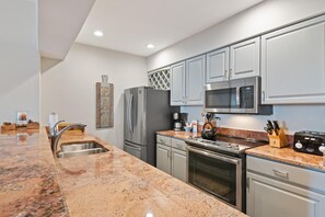 A modern kitchen with granite countertops, stainless steel appliances, and light-colored cabinetry. - Borders Lodge U204 1BD Beaver Creek Ski-in, Ski-out Condo (Avon)