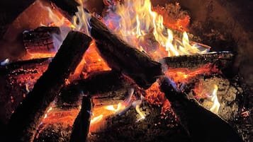 A fire burning in a circular metal fire pit with logs.