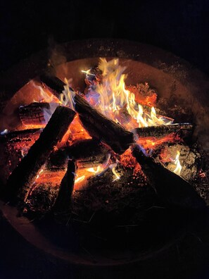 A fire burning in a circular metal fire pit with logs.