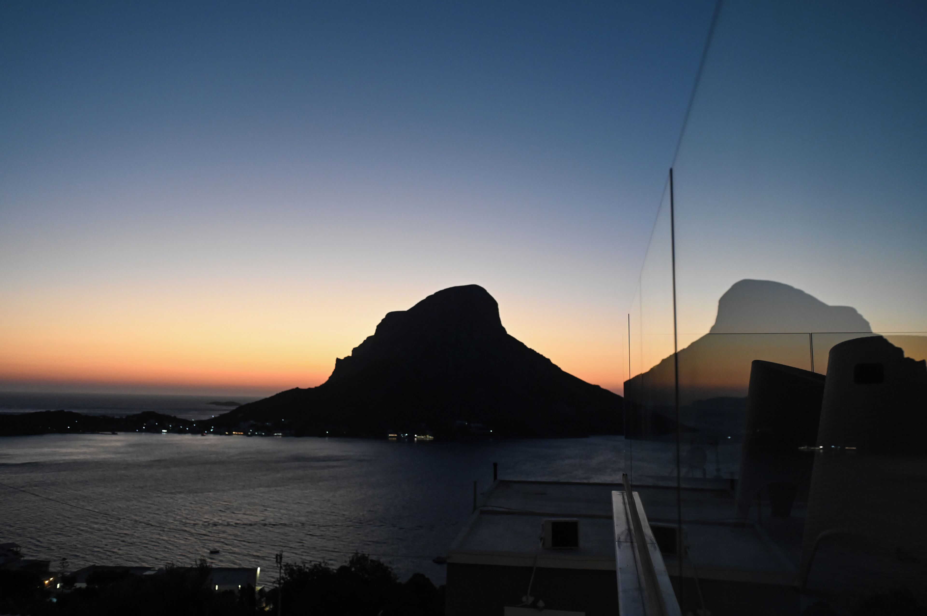 A coastal view with a prominent mountain silhouette during twilight.