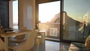 Ein modernes Interieur mit Essbereich, einer Couch und einer großen Schiebeglastür, die auf einen Balkon mit Bergblick führt.