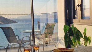 Ein Balkon mit Tisch, Stühlen, einem Hut und einer Serviertablett mit Gläsern und Speisen.