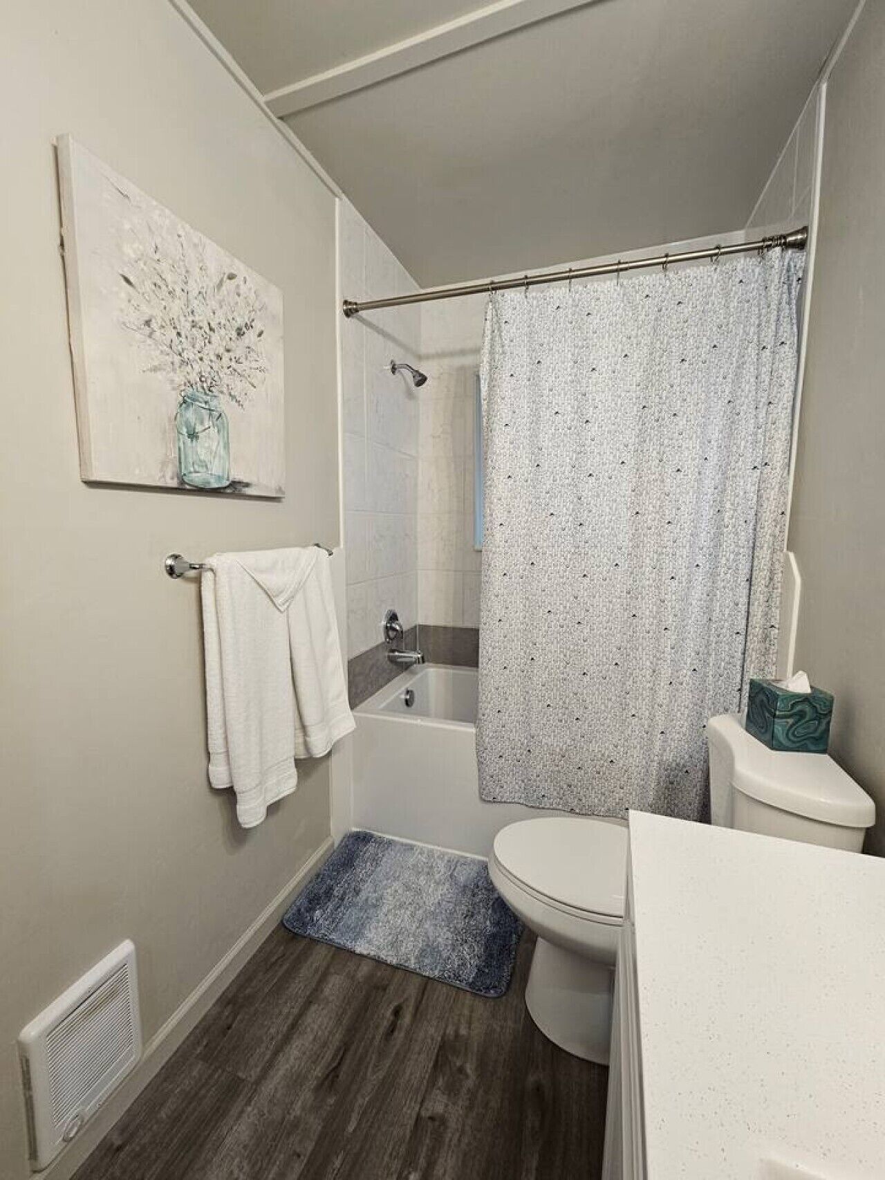 Een badkamer met douchegordijn, toilet, bad en handdoekhouder.