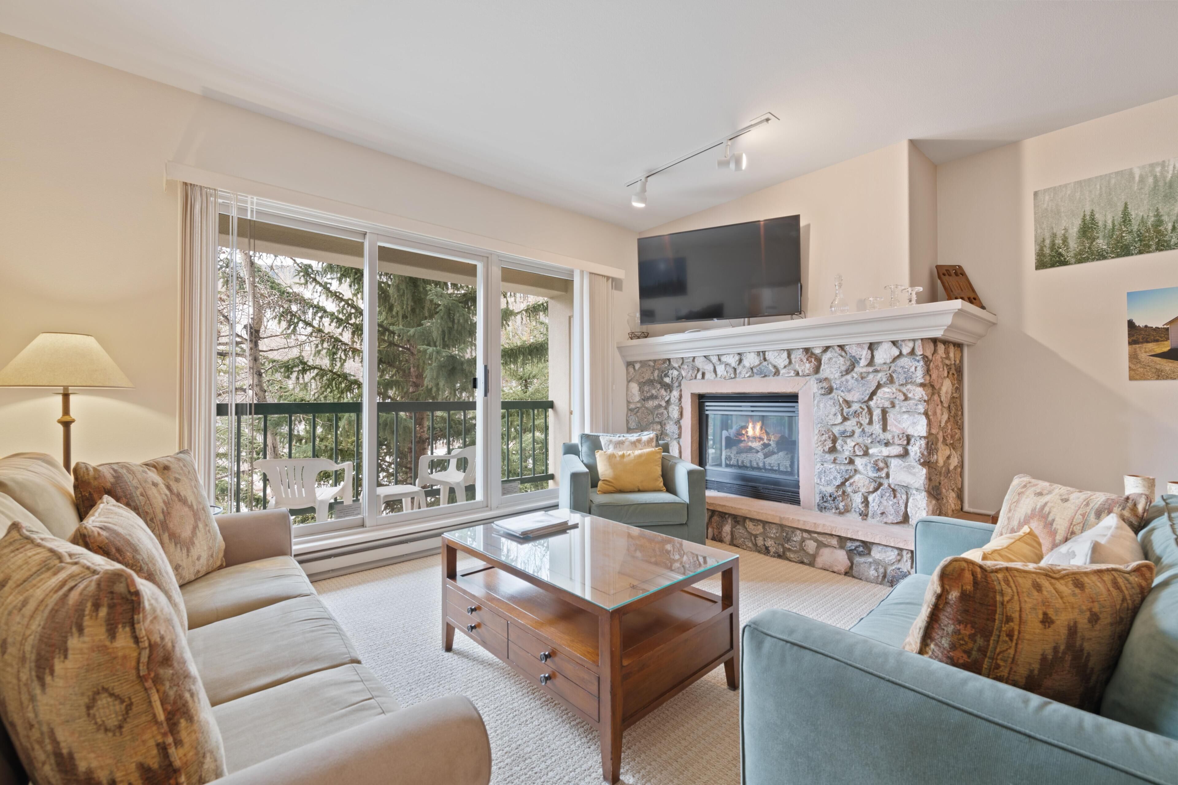 A living room with a stone fireplace, a sofa, a coffee table, and a television.