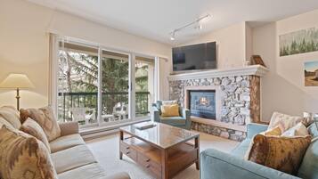 A living room with a stone fireplace, a sofa, a coffee table, and a television.