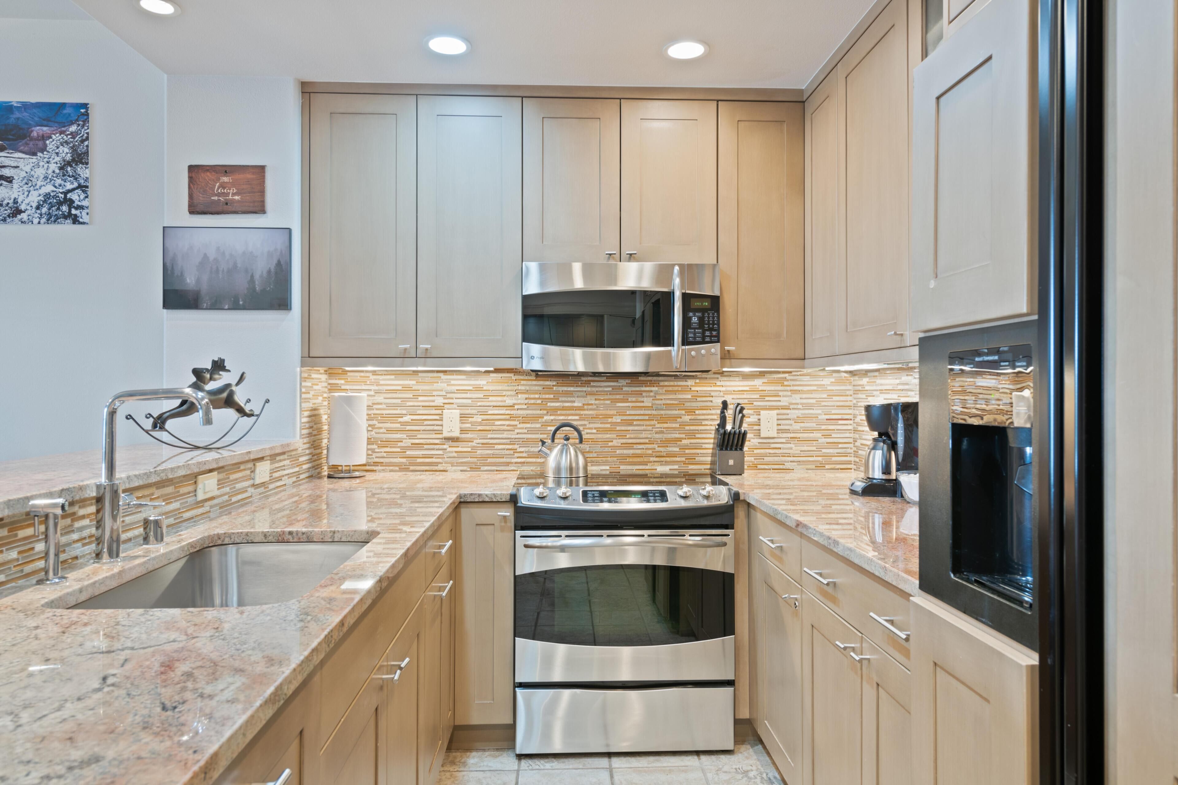 Una cocina moderna con electrodomésticos de acero inoxidable, armarios de madera y encimera de granito.