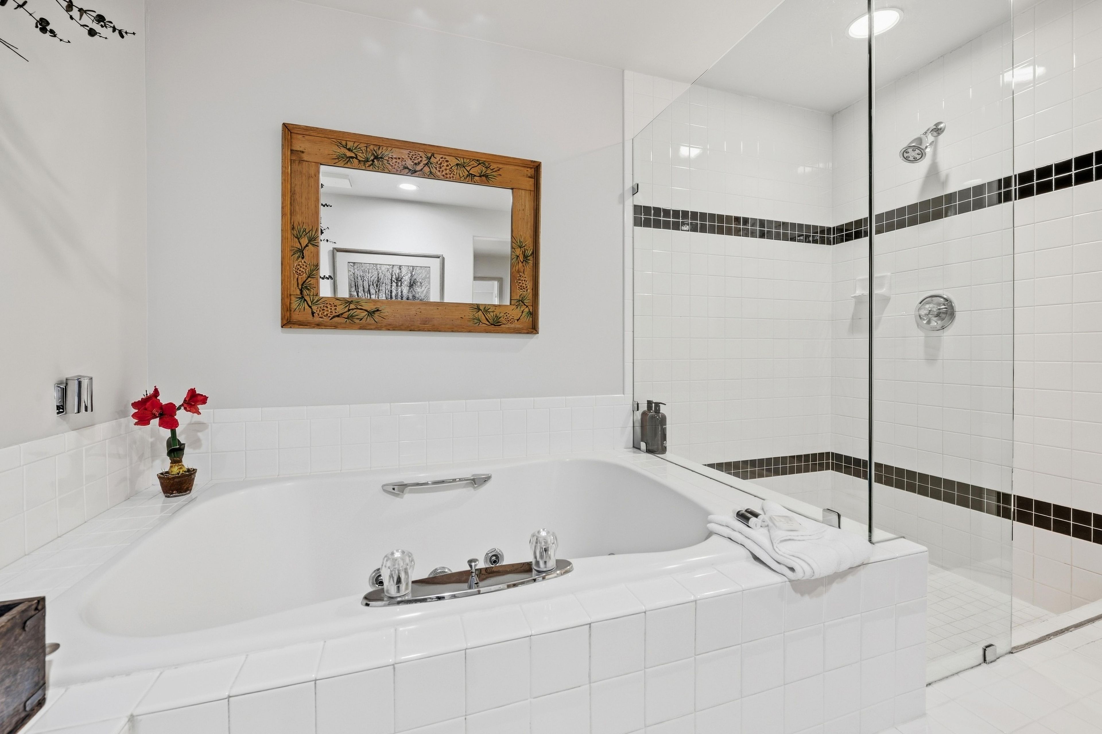 A modern bathroom with a freestanding bathtub, a glass-enclosed shower, and a wooden-framed mirror.