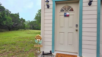 A house with a beige door, a welcome sign, a doormat, and two wall-mounted lanterns.