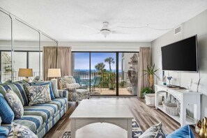 Ein Wohnzimmer mit einer Couch, Couchtisch, Fernseher und einem Balkon mit Blick.