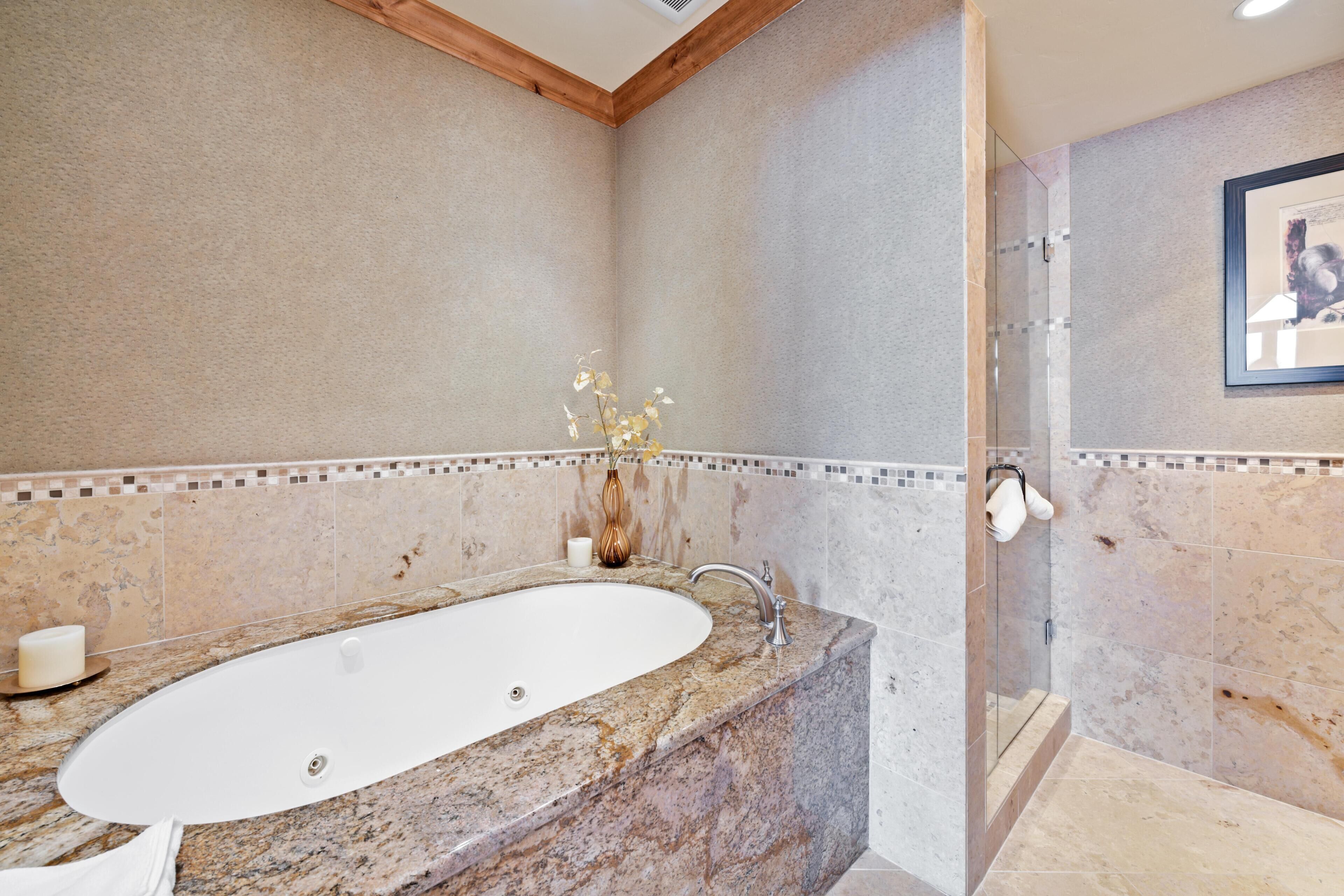 Un bany amb un lavabo de marbre, una cabina de dutxa de vidre i un quadre al mur.