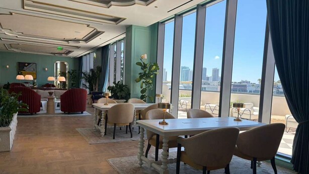 A hotel lobby with a dining area, large windows, and a view of the cityscape. - Luxury Designer Retreat in Wynwood / Skyline. 2BR. Pool & Bar (Miami)