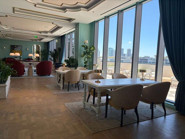 A hotel lobby with a dining area, large windows, and a view of the cityscape. - Luxury Designer Retreat in Wynwood / Skyline. 2BR. Pool & Bar (Miami)