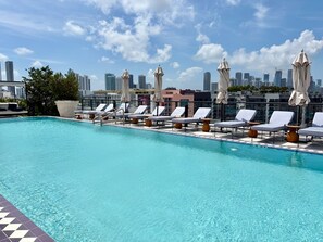 A rooftop pool with lounge chairs and umbrellas, a city skyline in the background. - Luxury Designer Retreat in Wynwood / Skyline. 2BR. Pool & Bar (Miami)