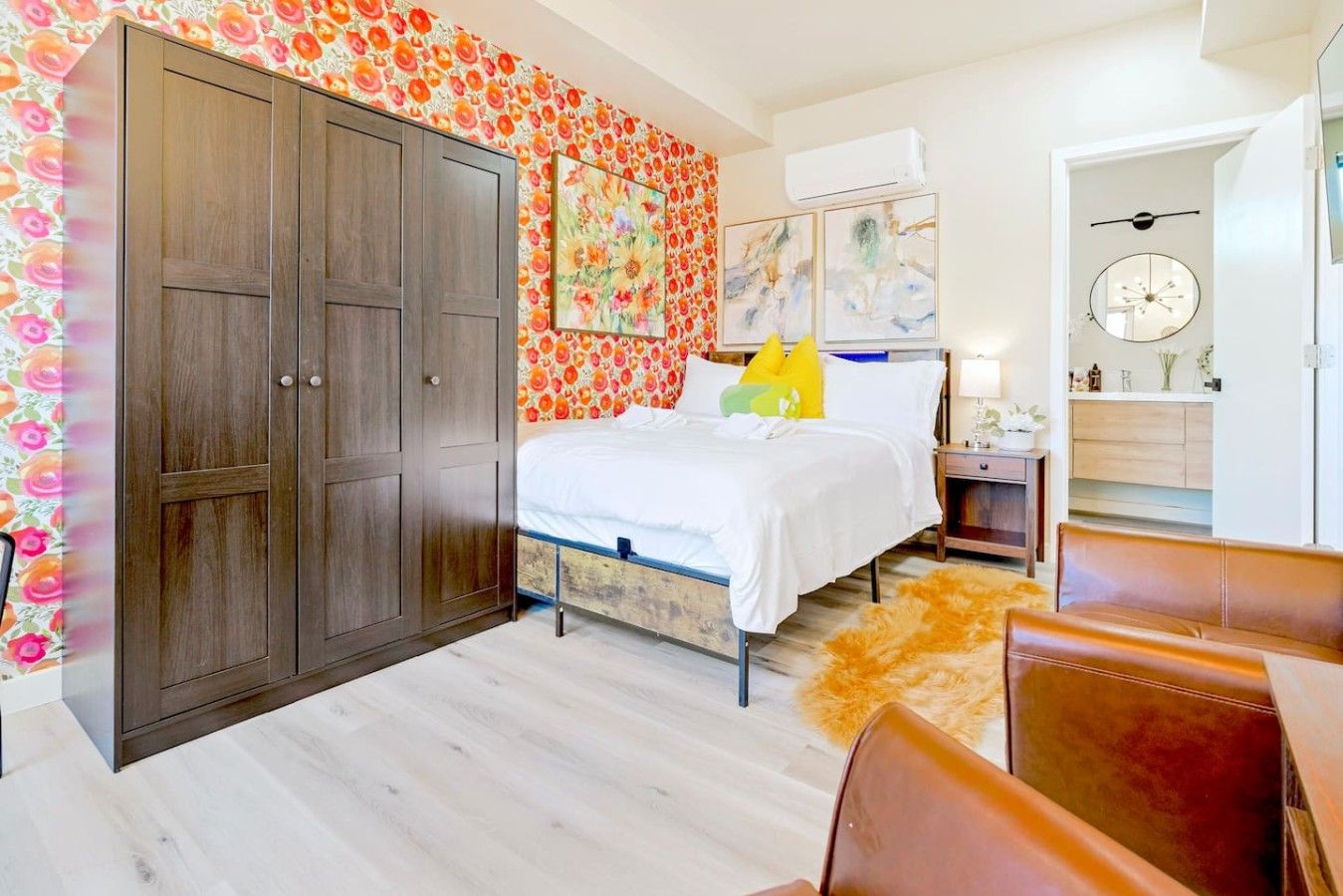 A bedroom with a bed, wardrobe, and a floral wallpaper design.