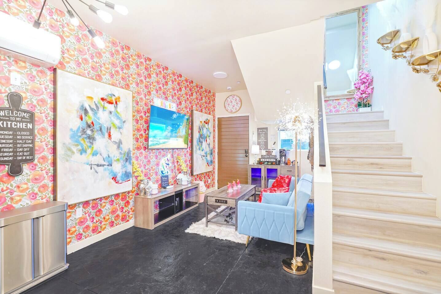 Een modern interieur met een trap, kunstwerken aan de muren, een koffiebar en een blauwe bank.