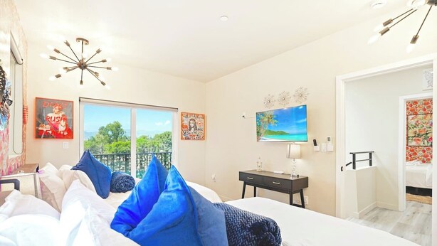 A hotel room with a bed, a desk, a chair, a TV, and a balcony with a view. - II. Chic 4BR Home by Universal + Patio + Grill + Parking (Los Angeles)