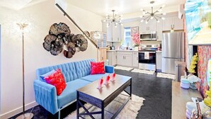 A modern kitchen with stainless steel appliances, a blue sofa with red cushions, and a unique wall art piece. - II. Chic 4BR Home by Universal + Patio + Grill + Parking (Los Angeles)