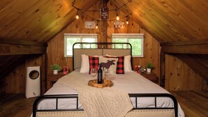 Un dormitorio acogedor en el ático, con cama, paredes de madera, una ventana, un calentador y un cartel con consejos para esquiar.
