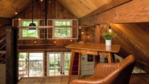 Un interior de madera con una habitación estilo loft, una mesa de comedor, un sillón de cuero y una planta en maceta.