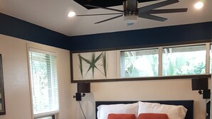 A bedroom with a bed, a ceiling fan, a window, and a chair. - Aloha Hideaways- Palm Retreat A (Princeville)