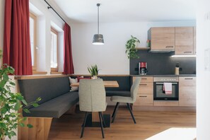 Eine moderne Küche mit Holzschränken, einem eingebauten Ofen und einem Essbereich mit einer Bank und Stühlen.