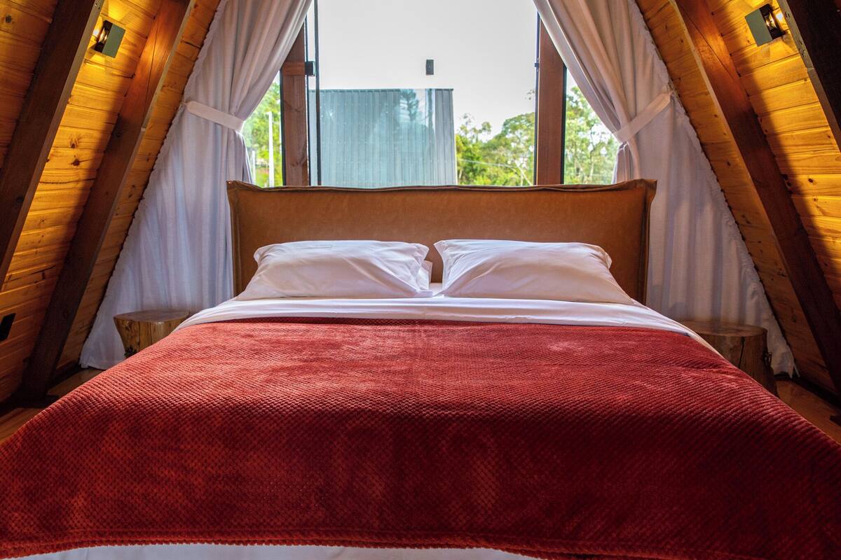 Una habitación con cama, ventana y cortinas.