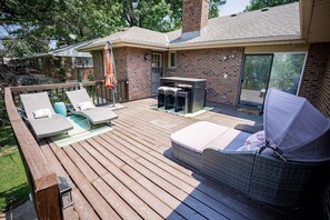 A deck with outdoor furniture, a grill, and a sliding glass door. - 5 Mins to Arrowhead | 3BR KC Retreat | 3 Ensuites, Sauna & Theater (Independence)