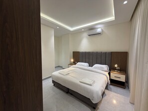 Ein modernes Hotelzimmer mit einem großen Bett, Nachttischen, einer Klimaanlage und Einbauleuchten.