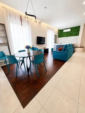 A modern living room with a dining area, a flat-screen TV, and a green wall feature. - Dreamora Charme & Relax in the heart of Salerno (Salerno)