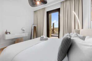 Ein modernes Hotelzimmer mit Bett, Schreibtisch, Stuhl und Blick ins Freie.